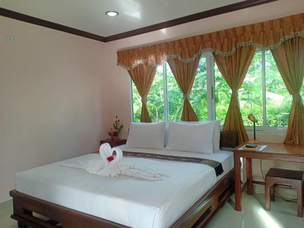 a bedroom with a bed with white sheets and a window at Capital O 75415 Nanthachart Riverview Resort in Samut Songkhram