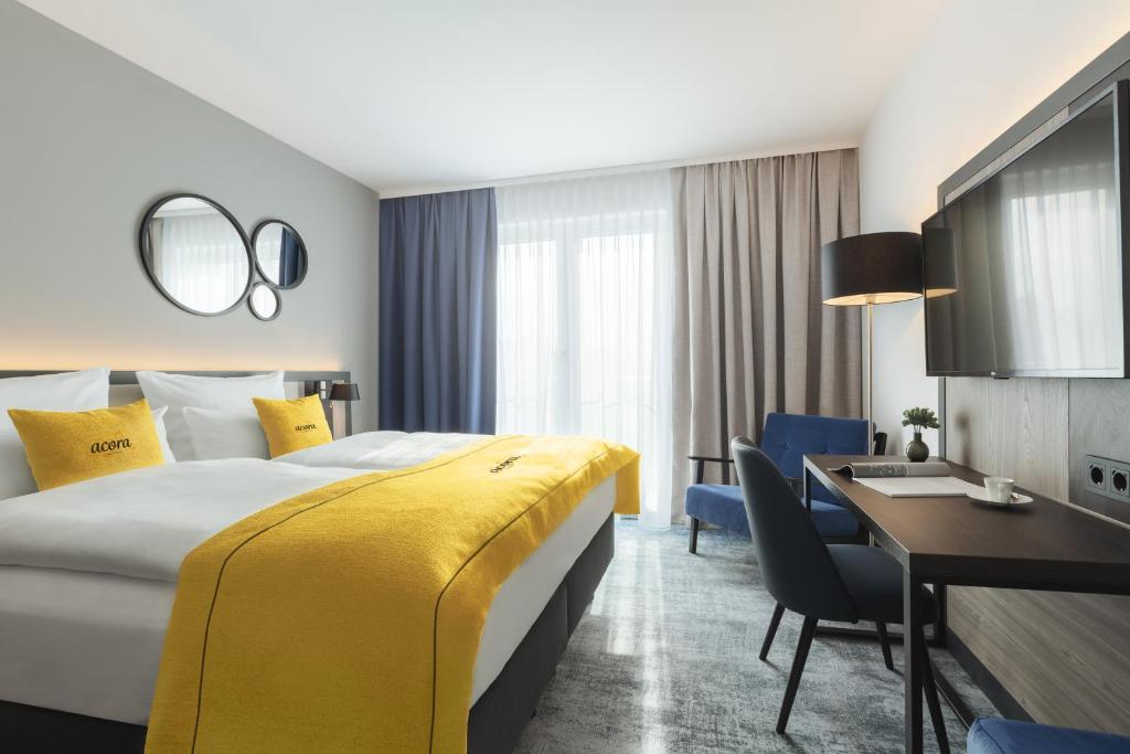 una camera d'albergo con un grande letto e una scrivania di acora Augsburg Living the City a Neusäß