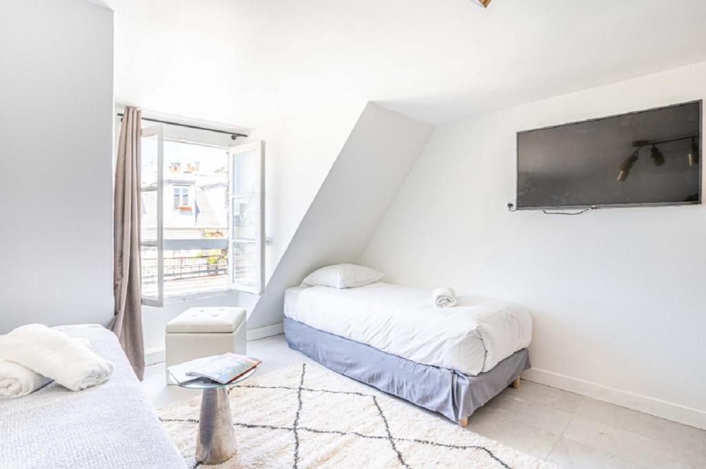 - une chambre avec 2 lits et une télévision murale dans l'établissement 145 - Urban Pretty Studio in Center of Paris, à Paris
