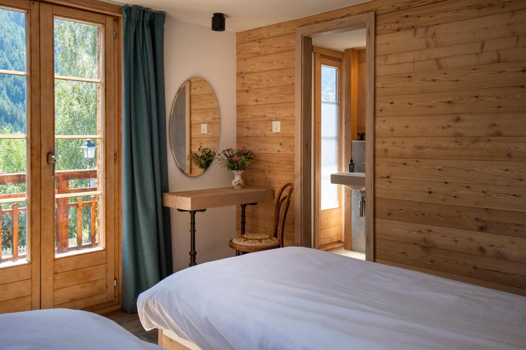 a bedroom with wooden walls and a bed and a mirror at La Bergère in Ayer