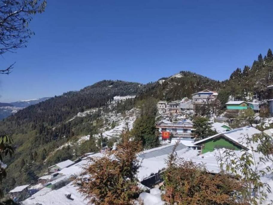a mountain with snow on the ground and buildings at Yuven House in Darjeeling