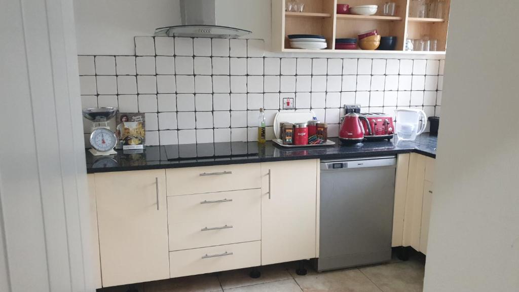 a kitchen with white cabinets and a red appliance at Fully Equipped Modern 3 bedroom House in Bishops Stortford
