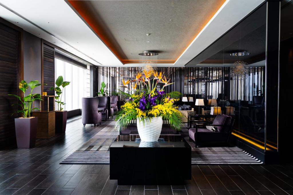a lobby with a vase of flowers on a table at Rihga Royal Gran Okinawa in Naha