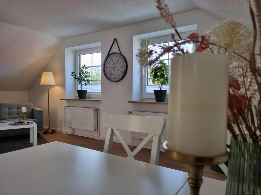 uma sala de estar com uma mesa e um relógio na parede em Ferienwohnung am Springerhof em Schönefeld