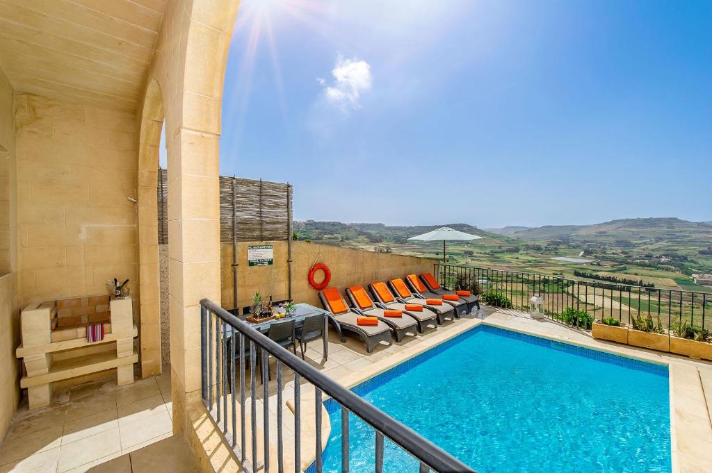 balcone con tavolo e sedie e piscina. di The Blue House Holiday Home a Għasri