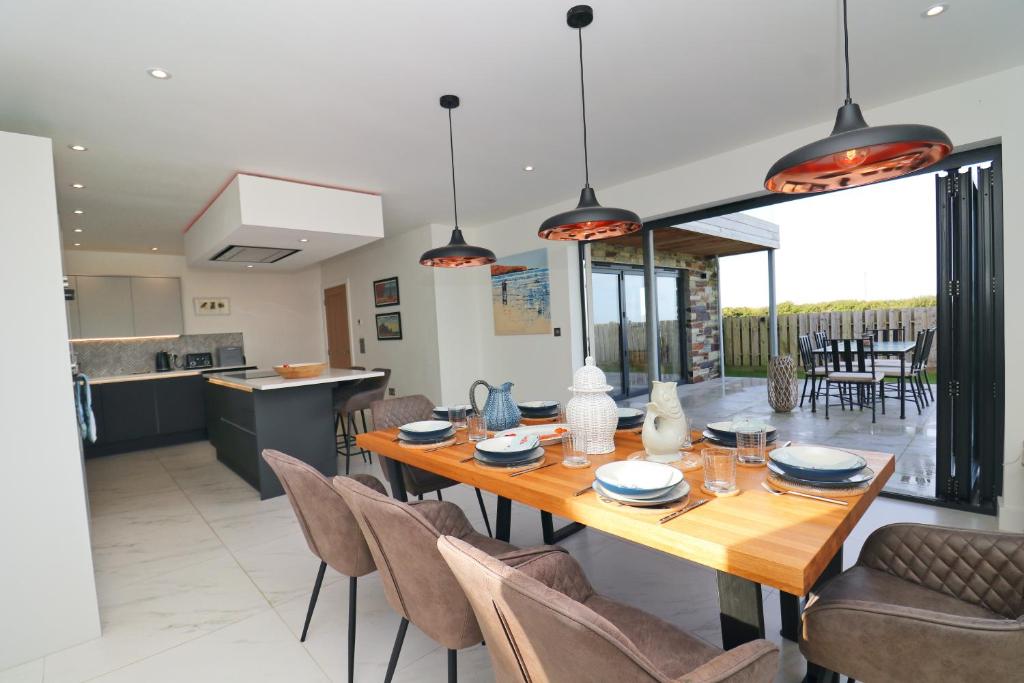 a kitchen and dining room with a wooden table and chairs at Stunning home, sea views, walk to beach in Saint Ervan