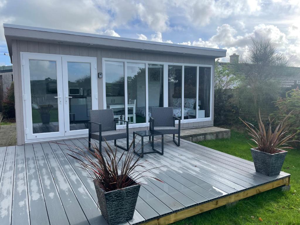 une terrasse en bois avec des chaises et une maison dans l'établissement The Garden Room - A cosy country stay in Cornwall, à Callington