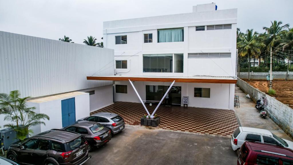a white building with cars parked in a parking lot at Marksman Resort in Bangalore