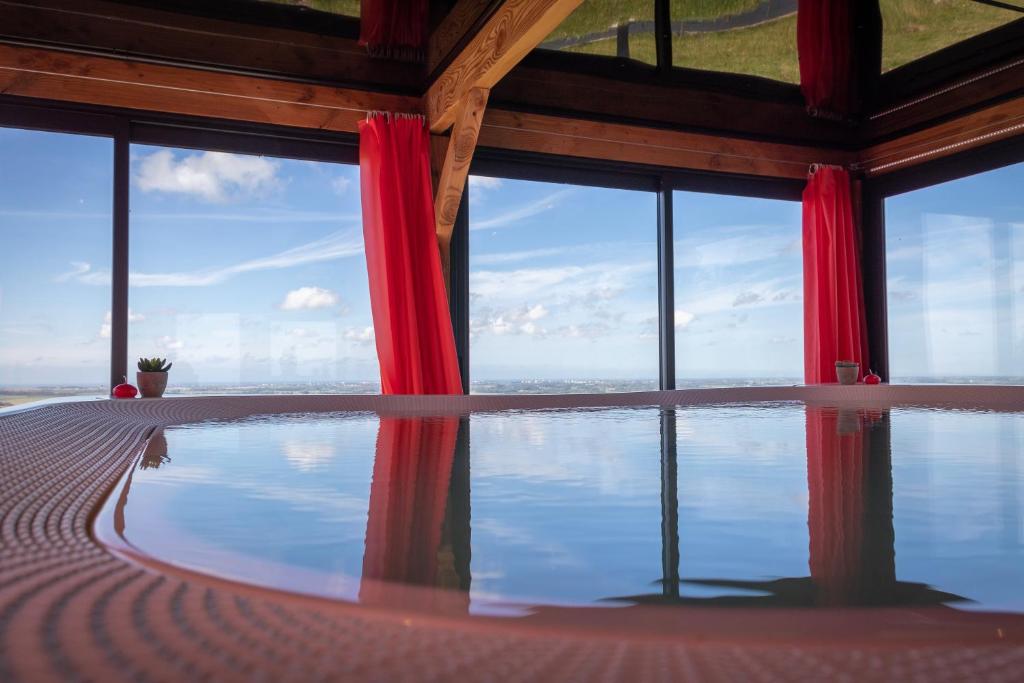 a room with a view of the water with red curtains at Gite La Ferme du Grand Air in Fiennes