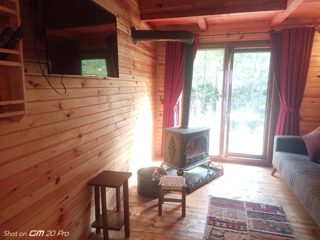 a living room with a couch and a stove in a room at MJORA Bungalov Ayder in Güroluk