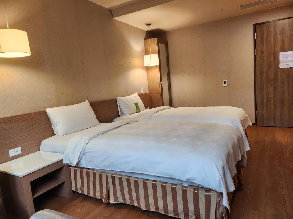 a hotel room with a large bed and a table at Kindness Hotel - Kaohsiung Main Station in Kaohsiung
