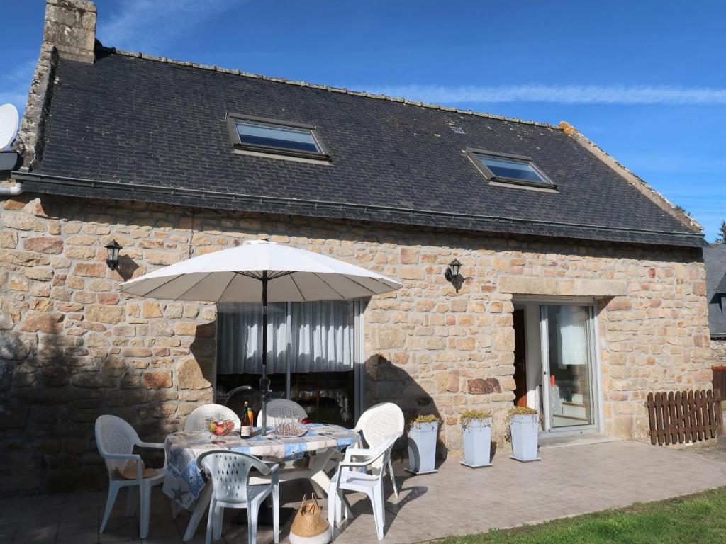 a table with an umbrella in front of a building at Holiday Home Ty Kerzo - PHM100 by Interhome in Plouhinec