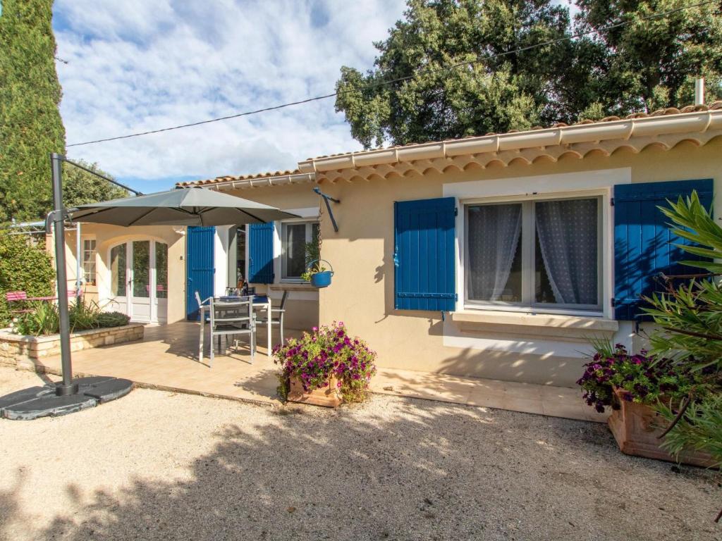 ein Haus mit blauen Fensterläden und einer Terrasse in der Unterkunft Holiday Home Les Amandiers - MZN100 by Interhome in Mazan