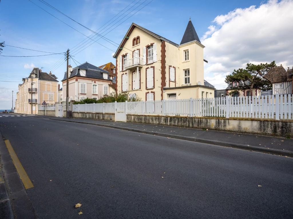 an empty street with a white fence and houses at Apartment Le Chalet by Interhome in Cabourg