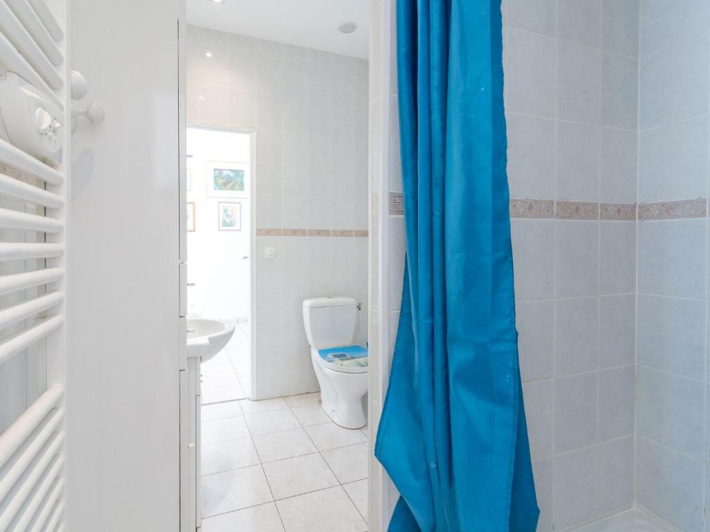 a bathroom with a toilet and a blue shower curtain at Apartment Le Chalet by Interhome in Cabourg