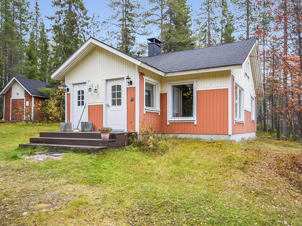 ein kleines weißes und orangefarbenes Haus in einem Hof in der Unterkunft Holiday Home Saapunkijärvi- pitkäperä by Interhome in Saapunki