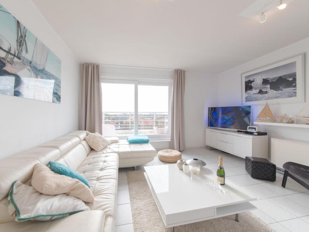 ein weißes Wohnzimmer mit einem Sofa und einem Tisch in der Unterkunft Apartment Wilde Zee by Interhome in Bredene-aan-Zee