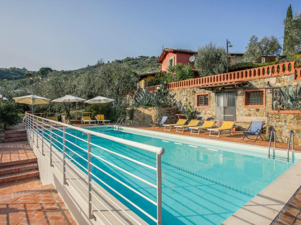 a swimming pool with chairs and umbrellas next to a building at Holiday Home Borgo della Limonaia-3 by Interhome in Pieve a Nievole