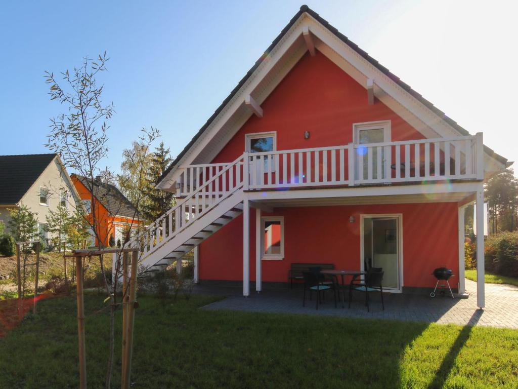a red house with a deck and a table at Apartment Müritz Ferienpark Röbel-8 by Interhome in Röbel