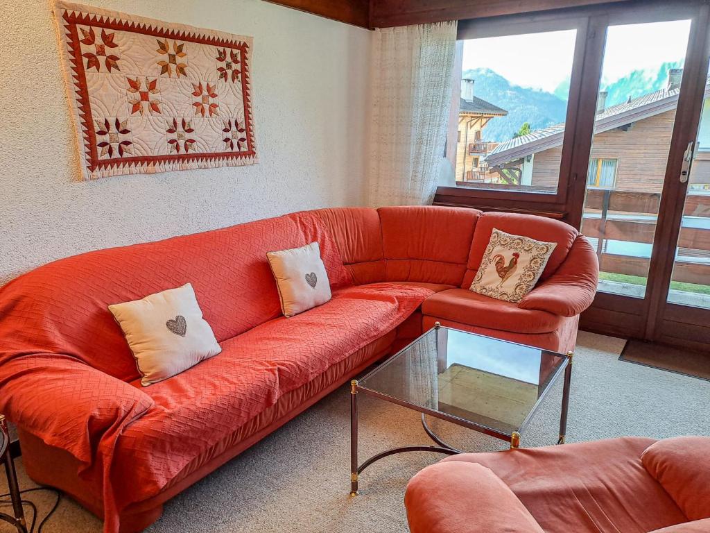 ein Wohnzimmer mit einem roten Sofa und einem Glastisch in der Unterkunft Apartment Lichen 4 by Interhome in Verbier