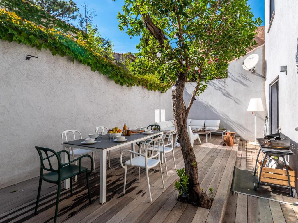 patio ze stołem, krzesłami i drzewem w obiekcie Holiday Home St Cyprien Plage by Interhome w mieście San Ciprianu