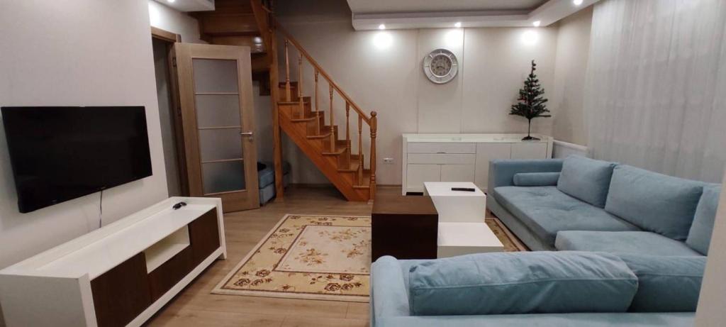a living room with a blue couch and a tv at Duplex 41 in the city center of Umraniye Alemdag caddesi Istanbul in Sarıgazi