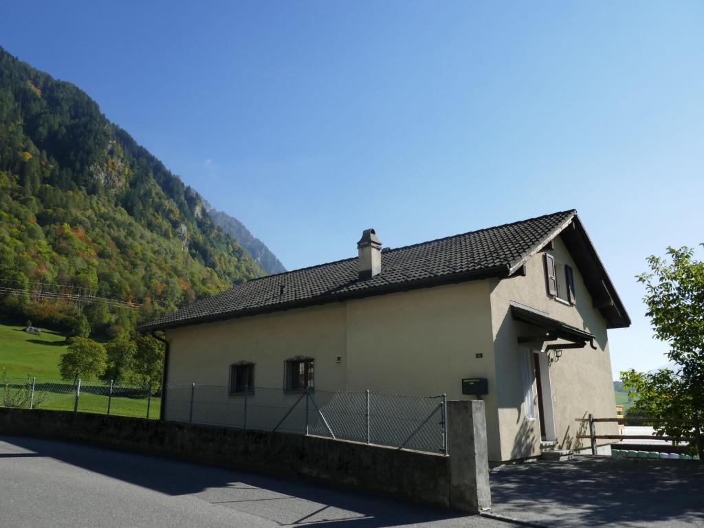 Un petit bâtiment blanc avec des montagnes en arrière-plan dans l'établissement Holiday Home Casa Al Noce by Interhome, à Olivone