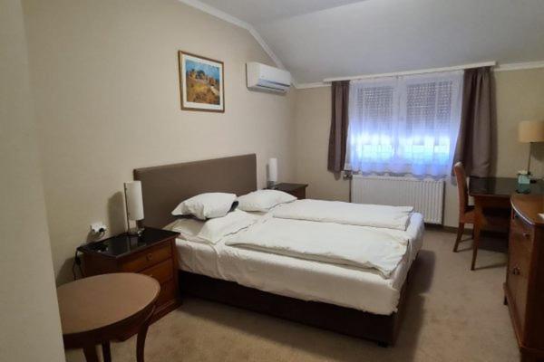 een slaapkamer met een bed, een tafel en een bureau bij Korona Panzió in Hatvan