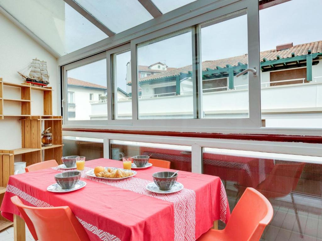 - une salle à manger avec une table rouge, des chaises et des fenêtres dans l'établissement Apartment Albarade by Interhome, à Saint-Jean-de-Luz