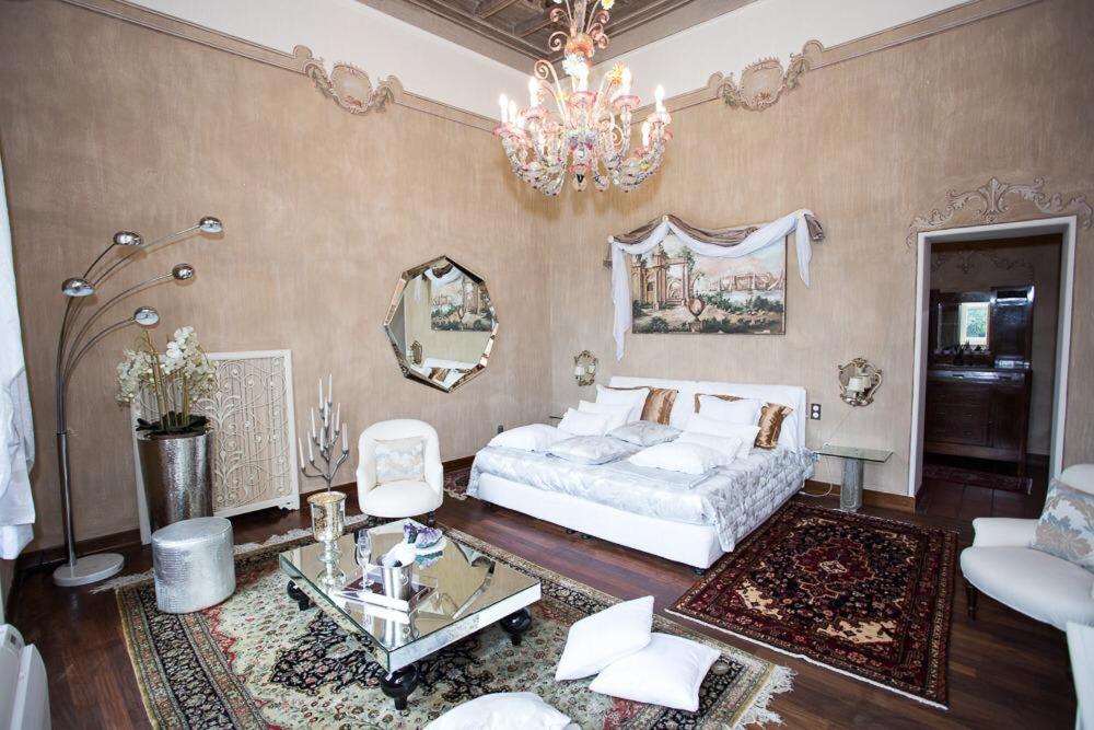 a bedroom with a white bed and a chandelier at Villa Ghiringhelli in Azzate