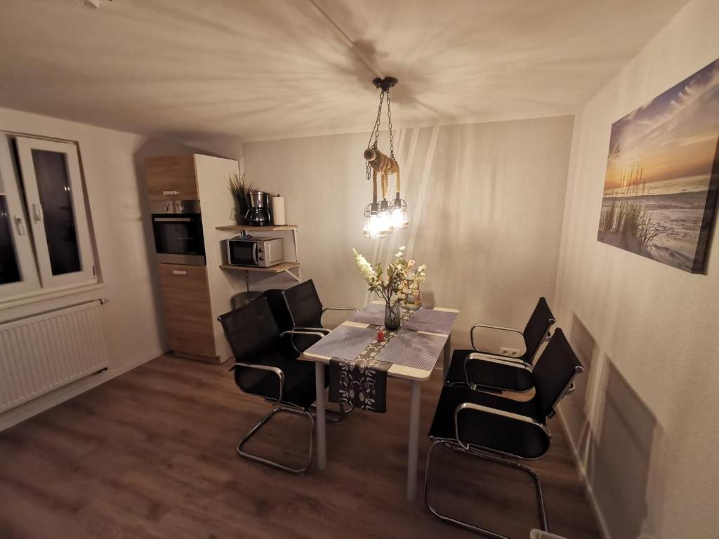 a dining room with a table and black chairs at Mansarde Ferienwohnung - Modern - Zentral - PayTV in Wilhelmshaven