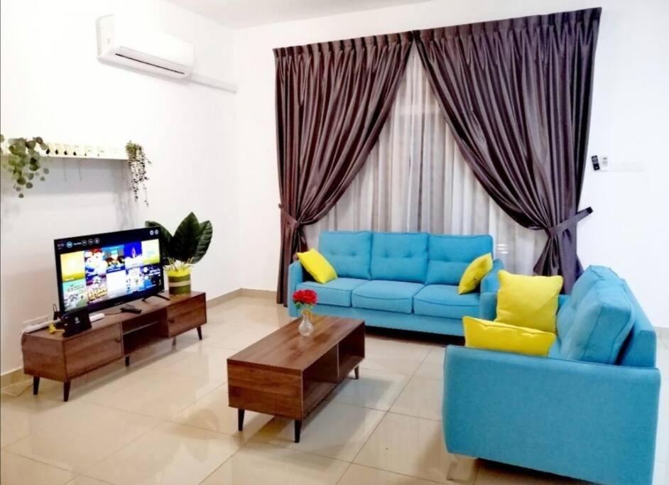 sala de estar con sofá azul y TV en Desaru Sweet and Cozy Home,11pax, Mini Pool, Beach ,Waterpark, Wifi, BBQ, en Bandar Penawar