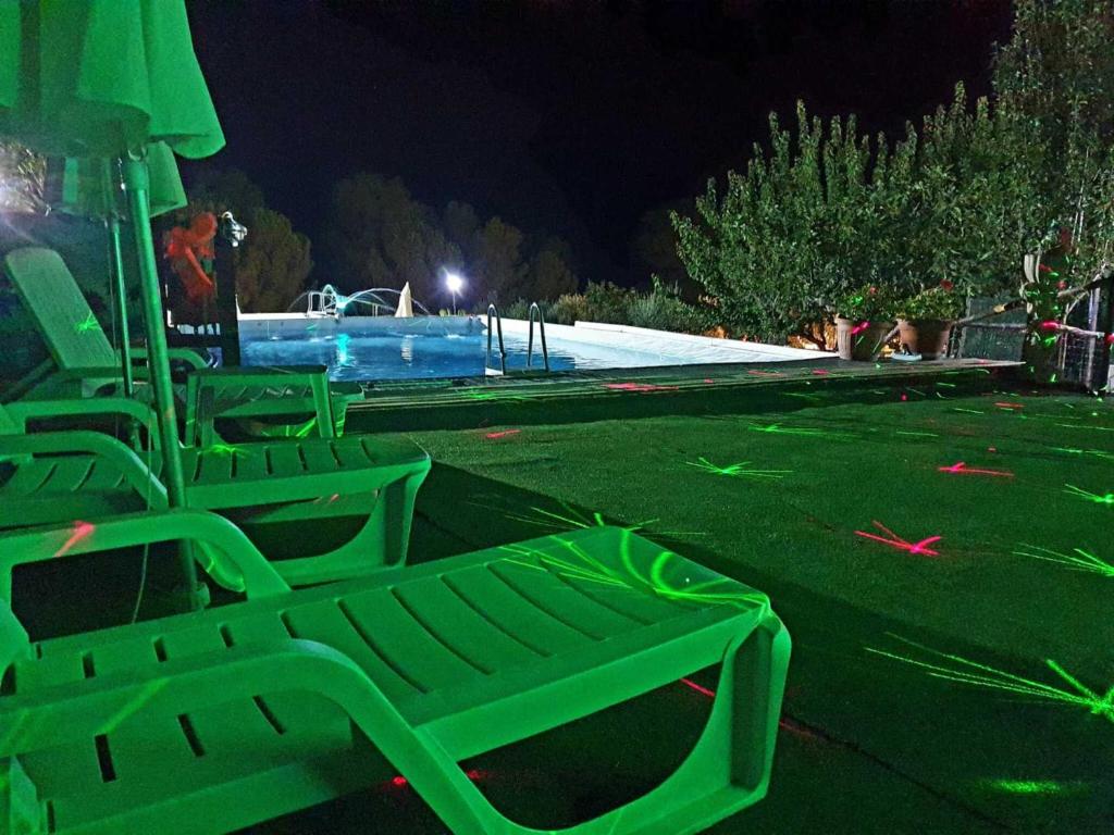 um grupo de cadeiras verdes em frente a uma piscina em Villa Parco Morello Piano Terra em Villarosa
