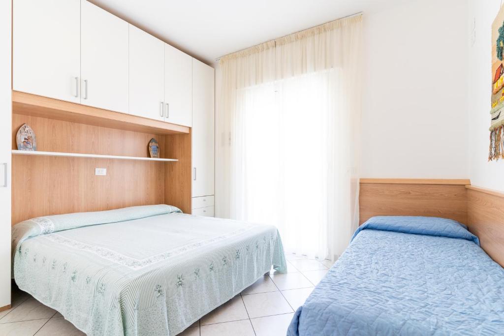 een slaapkamer met twee bedden en een raam bij Ca' Mira Apartments in Caorle