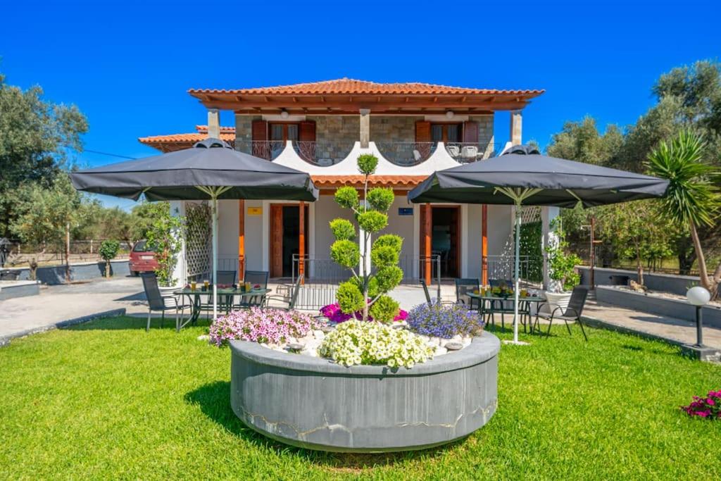 a house with a garden with umbrellas at Afroditi Holiday Home- Green View Apartment in Svoronata