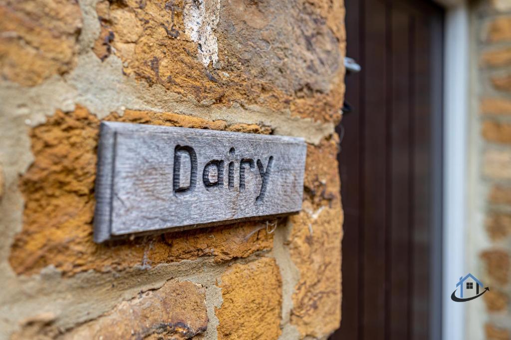 ein Schild an einer Ziegelmauer mit dem Wort Molkerei in der Unterkunft The Old Plough, rustic flat, super king bed or twins, en-suite, secure parking, free wi-fi, corporates welcome in Caldecott