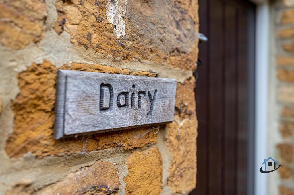 a sign on a brick wall with the word dairy at The Old Plough, rustic flat, super king bed or twins, en-suite, secure parking, free wi-fi, corporates welcome in Caldecott