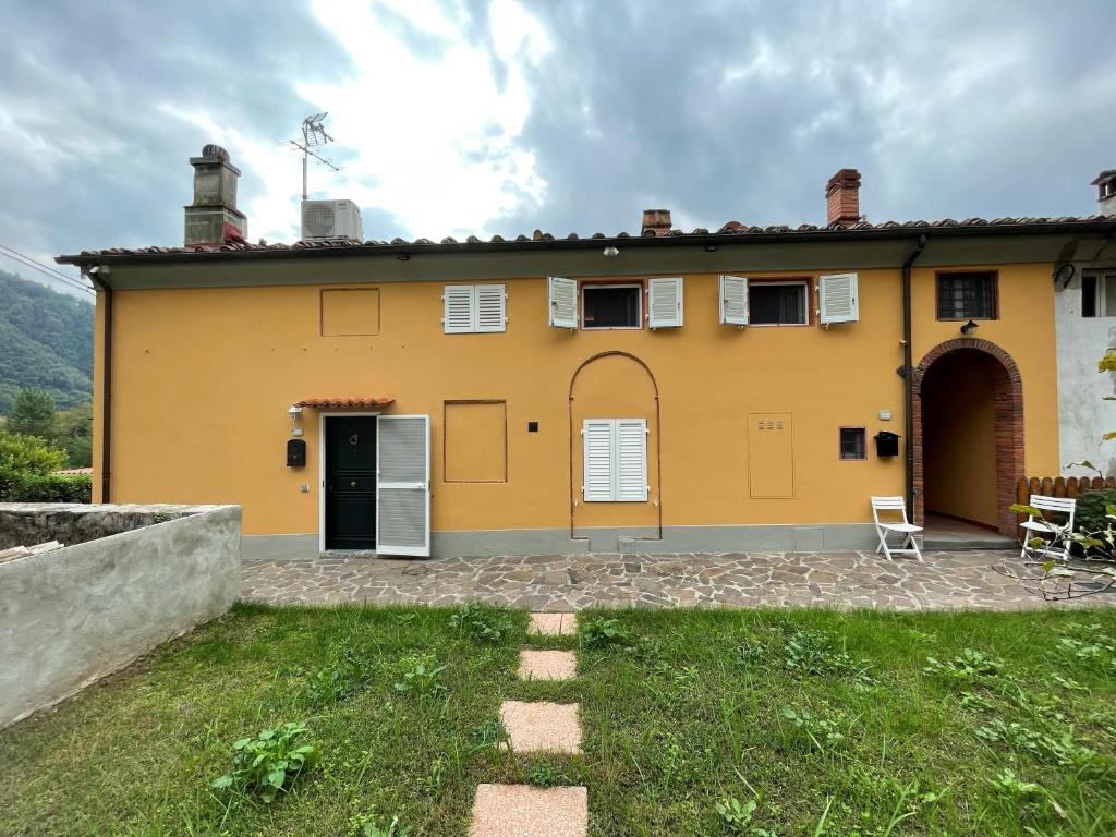una casa amarilla con dos sillas en un patio en La Casa Di Emma, en Lucca