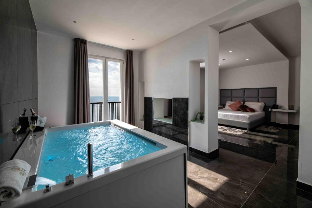 ein Badezimmer mit einer großen Badewanne mit einem Bett im Hintergrund in der Unterkunft GRAND HOTEL SERAPIDE in Pozzuoli