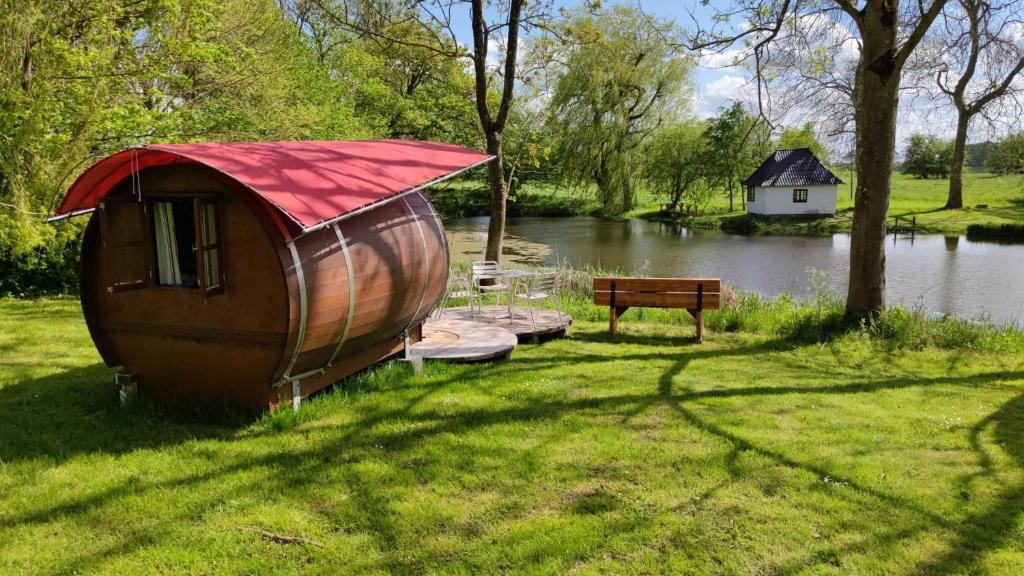 a small boat sitting on the grass next to a lake at Schlummerfass in Stoltebüll