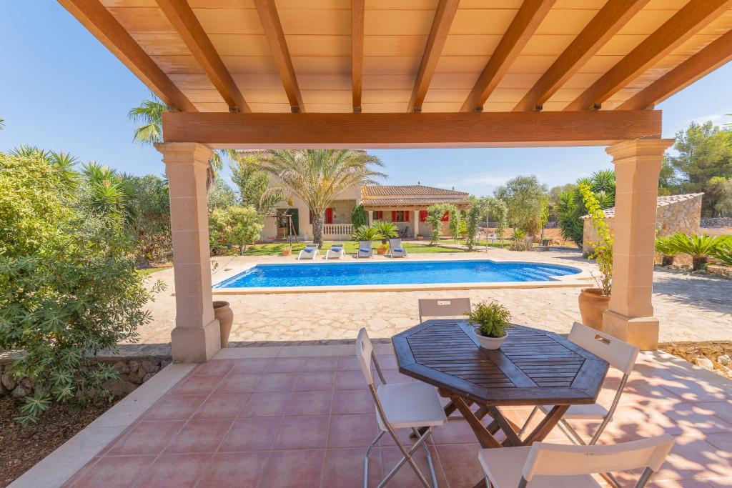 un patio con tavolo e sedie di fronte alla piscina di Villa Can Llinàs a Sencelles
