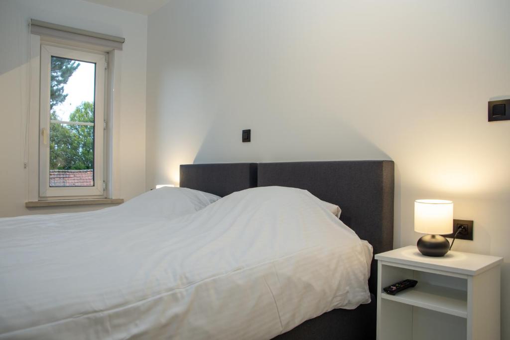 a bedroom with a large white bed with a window at Hotel Swaenenburg in Oostrozebeke