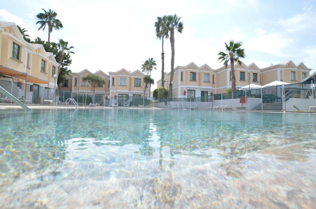 a large swimming pool with palm trees and houses at Complejo Sun's Gardens - Maspalomas in Maspalomas