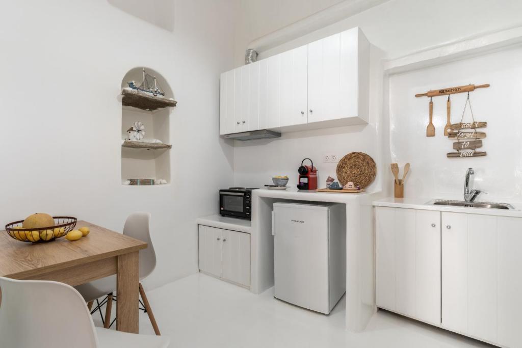 Biała kuchnia z białymi szafkami i stołem w obiekcie Love suite mykonos town w mieście Mykonos