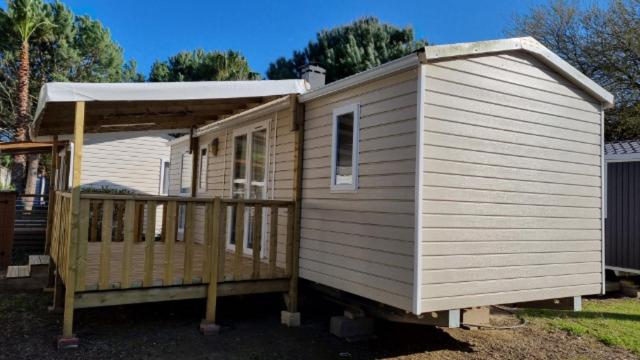 a small house with a porch and a deck at MOBIL HOME 6 pers à ST CYPRIEN 66 in Saint-Cyprien