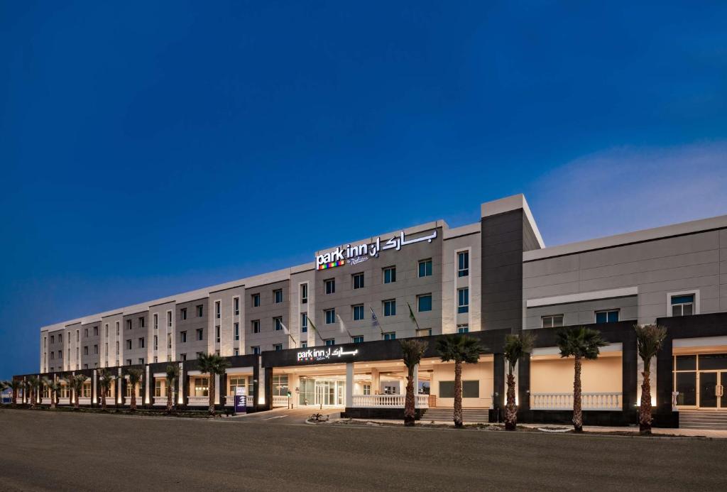 a large building with palm trees in front of it at Park Inn by Radisson Jubail Industrial City in Al Jubail