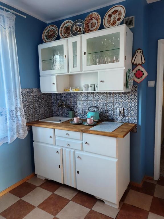 een keuken met witte kasten en blauwe muren bij Stylowe PRLove - Dom Dyrektora in Rogowo