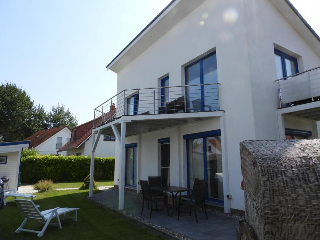 uma casa branca com uma varanda, uma mesa e cadeiras em Bodden-Adler em Fuhlendorf