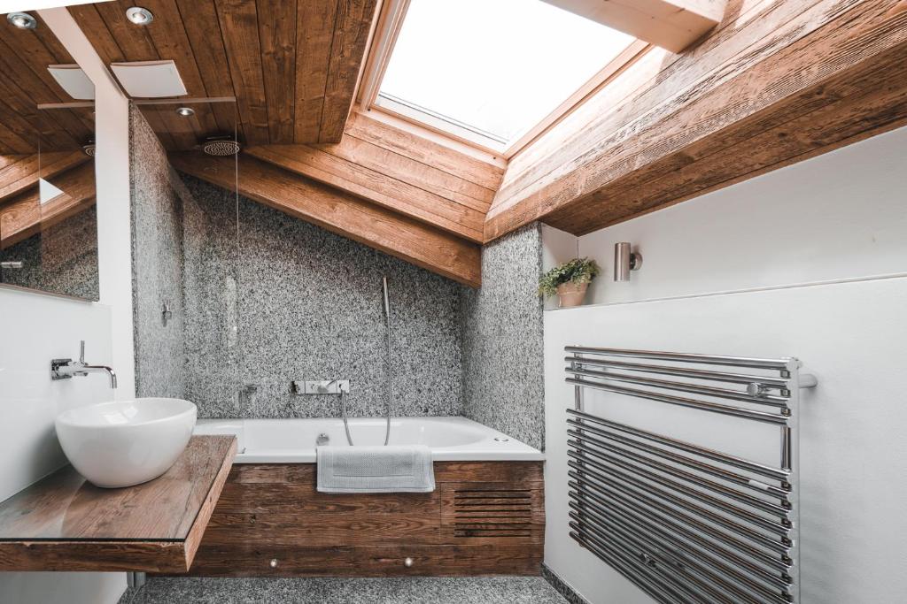 a bathroom with a tub and a sink and a skylight at Chalet Jessica in Saas-Fee