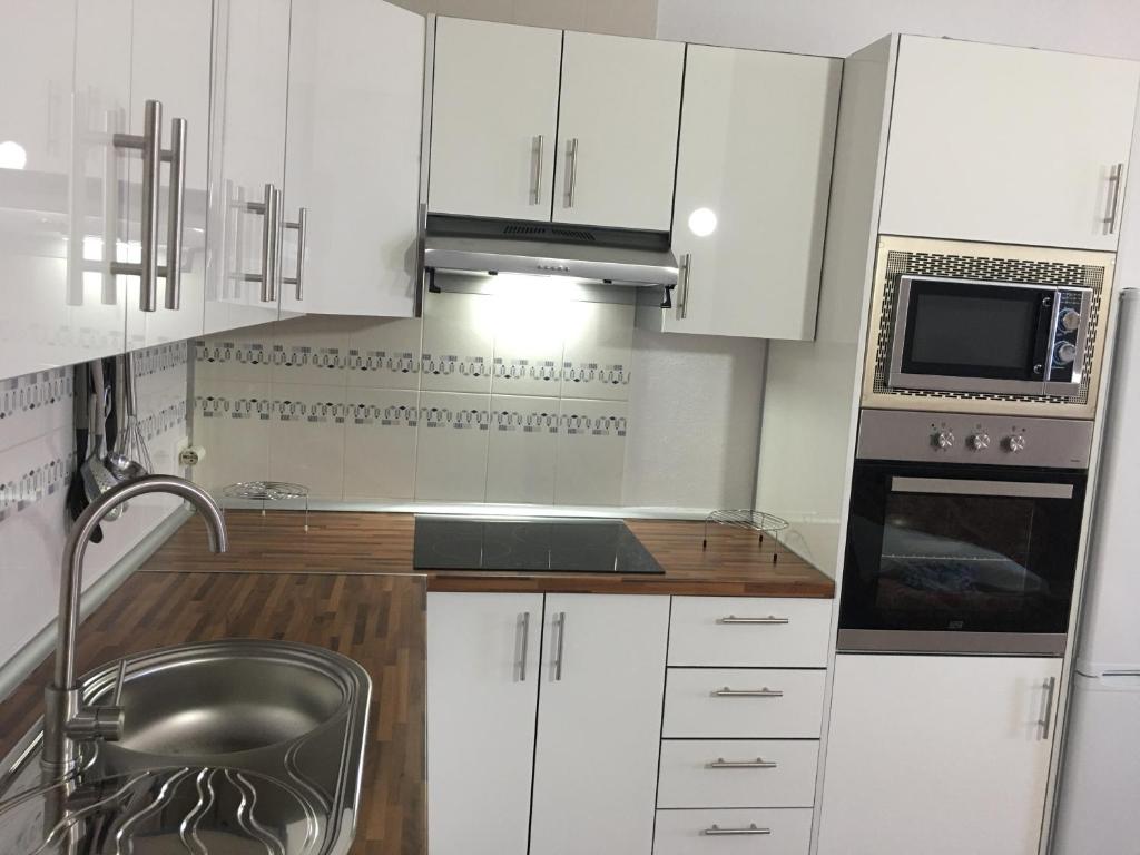 a kitchen with white cabinets and a sink and a microwave at Apto Tagoro, La Restinga in La Restinga